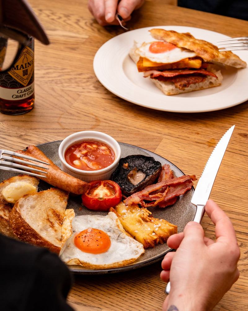 Hand assembling a bacon and egg breakfast sandwich at The Focacceria on Boucher Road Belfast